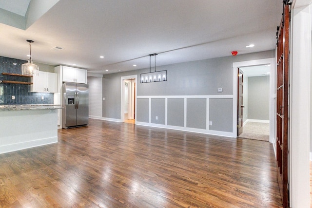 unfurnished living room with a barn door and dark hardwood / wood-style floors