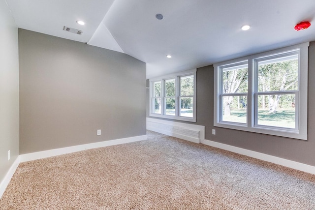 carpeted empty room featuring vaulted ceiling