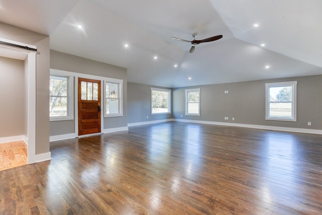 unfurnished living room featuring ceiling fan, a barn door, dark hardwood / wood-style floors, plenty of natural light, and lofted ceiling