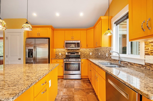 kitchen with appliances with stainless steel finishes, a wealth of natural light, and decorative light fixtures