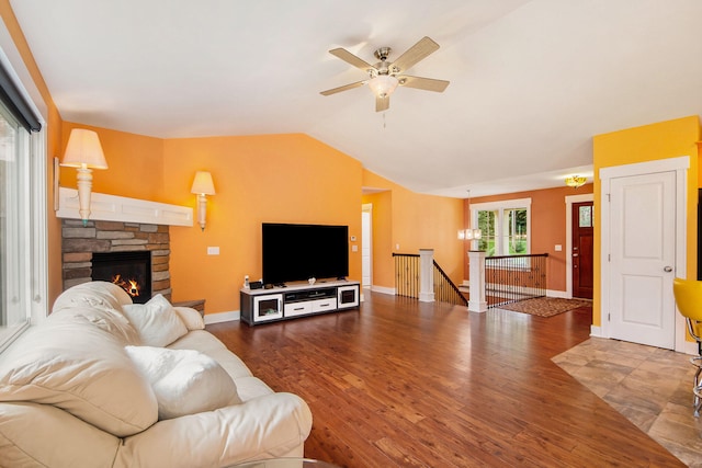 living room featuring lofted ceiling, hardwood / wood-style floors, ceiling fan, and a stone fireplace