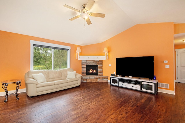 living room featuring ceiling fan, dark hardwood / wood-style floors, vaulted ceiling, and a stone fireplace