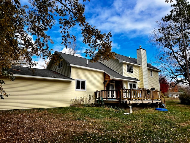 rear view of property featuring a wooden deck and a lawn