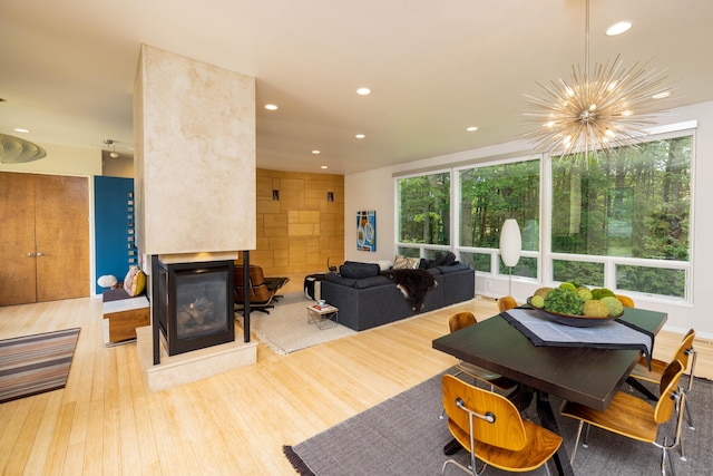 12737 Sanctuary Pl, Grand Haven, MI 49417 - dining area featuring a chandelier, recessed lighting, wood finished floors, and a multi sided fireplace