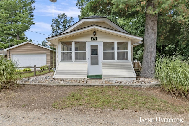 view of front of house featuring an outbuilding, a garage, and a sunroom