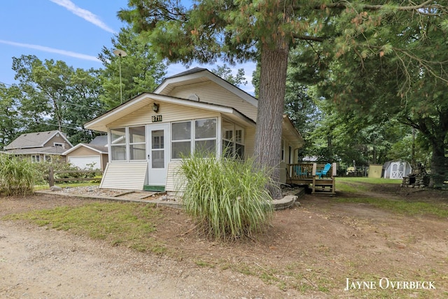 view of front of home with a sunroom, a deck, and a storage unit