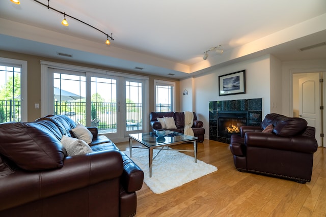 living room featuring track lighting, light hardwood / wood-style floors, and a high end fireplace