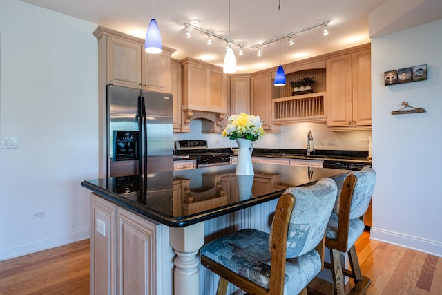 kitchen with dark stone counters, a kitchen island, stove, and stainless steel refrigerator with ice dispenser