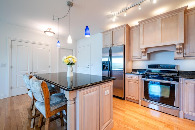 kitchen with light wood finished floors, appliances with stainless steel finishes, a breakfast bar, and a center island