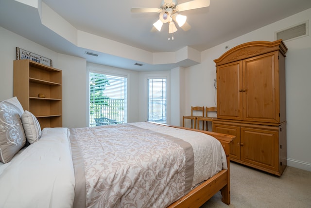 carpeted bedroom with ceiling fan and a raised ceiling