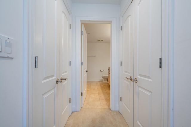 hall with light carpet and light tile patterned flooring