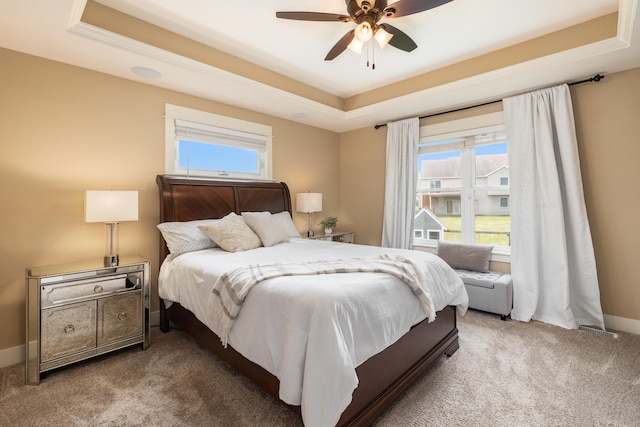 carpeted bedroom featuring ceiling fan and a raised ceiling