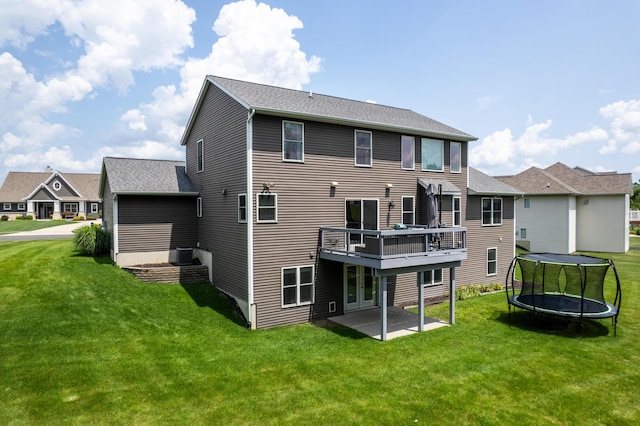 rear view of property with a patio, a deck, a trampoline, and a lawn