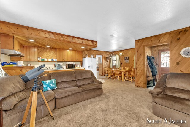 carpeted living room featuring lofted ceiling with beams and wooden walls