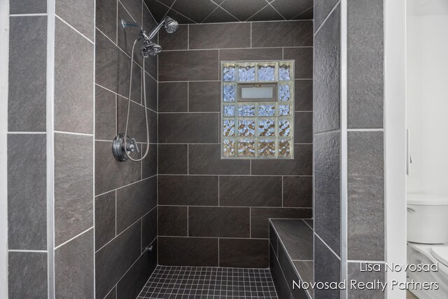 bathroom with toilet and a tile shower