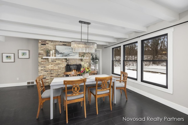 dining space featuring beam ceiling and a brick fireplace