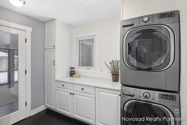 laundry room with stacked washer / drying machine and cabinets