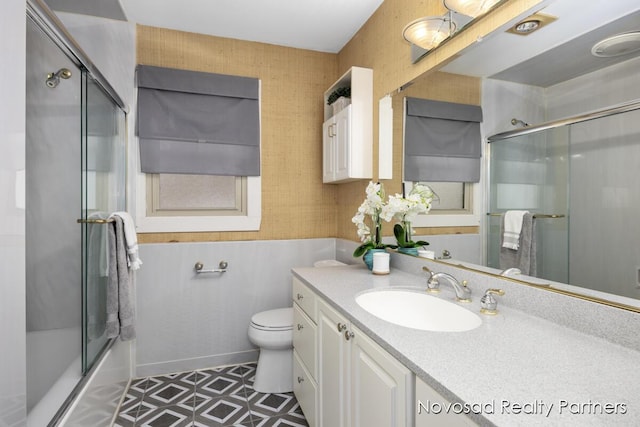 full bathroom with bath / shower combo with glass door, vanity, and toilet