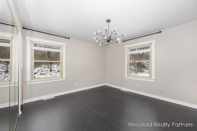 unfurnished room featuring dark hardwood / wood-style floors and an inviting chandelier