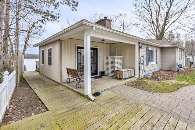 rear view of house with a chimney, a wooden deck, and fence