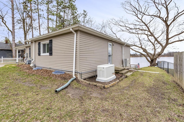 exterior space with a water view, fence, and a lawn