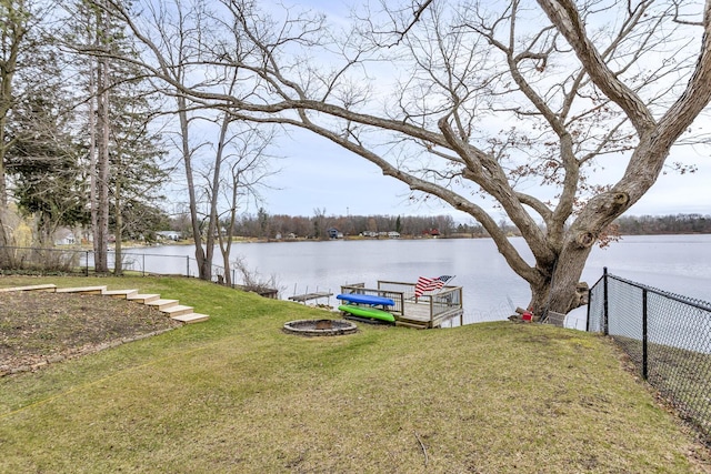 view of yard featuring a water view, a boat dock, and fence