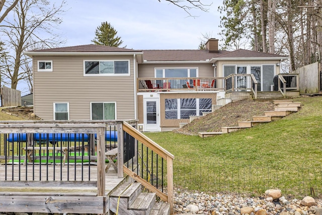 back of house featuring a wooden deck, a lawn, and a chimney