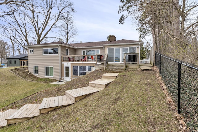 rear view of property with a yard, a deck, a fenced backyard, and a chimney