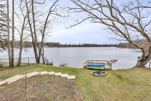 view of yard with a water view, a boat dock, and fence