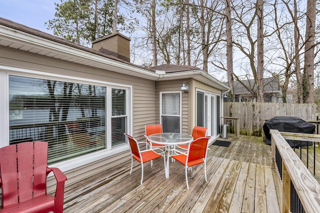 deck with outdoor dining space, fence, and area for grilling