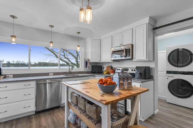 kitchen featuring stainless steel appliances, stacked washing maching and dryer, a sink, and wooden counters