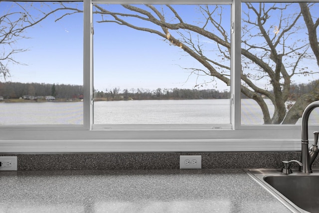 unfurnished sunroom featuring a sink, a water view, and a healthy amount of sunlight