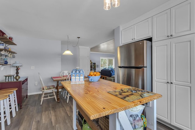 kitchen featuring dark wood finished floors, baseboards, white cabinetry, and hanging light fixtures