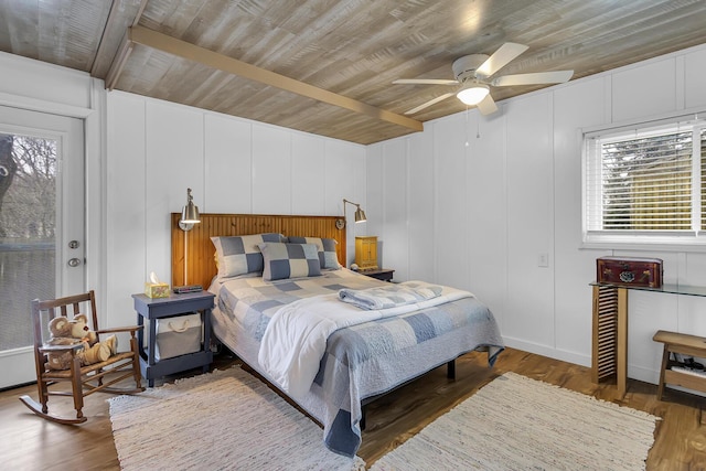 bedroom with a decorative wall, wood finished floors, and wood ceiling