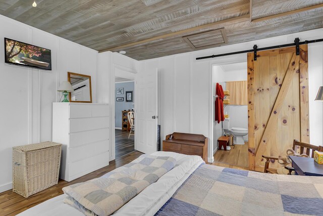 bedroom with wood ceiling, wood finished floors, ensuite bath, and a barn door