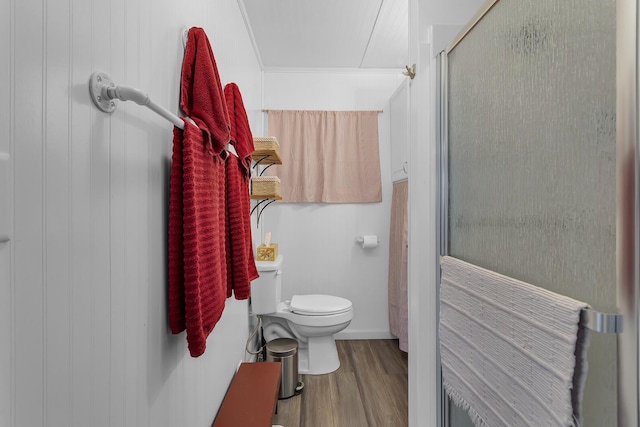 bathroom with toilet, a stall shower, and wood finished floors