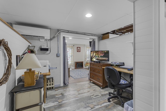 office with wood finished floors, a wall mounted air conditioner, and concrete block wall