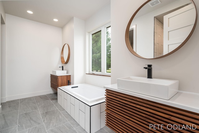 bathroom with vanity and tiled bath