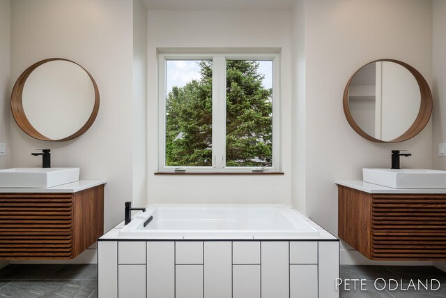 bathroom with vanity and tiled tub