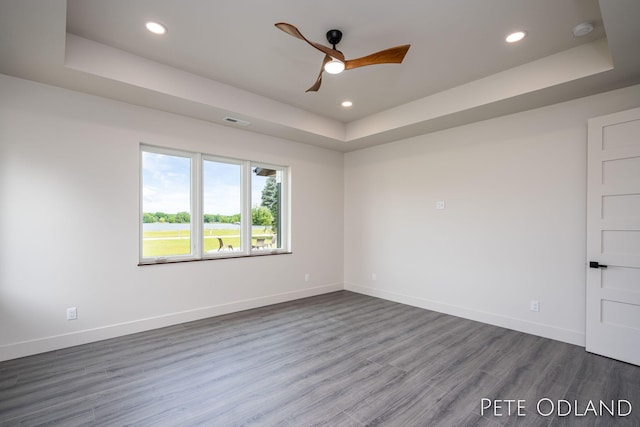 spare room featuring hardwood / wood-style flooring, a raised ceiling, and ceiling fan