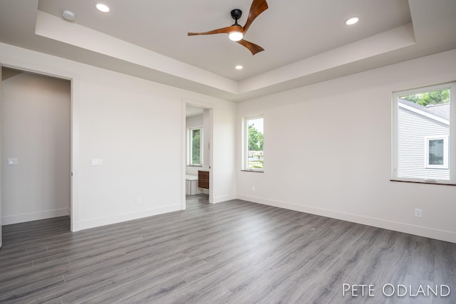 empty room featuring hardwood / wood-style floors, a tray ceiling, and ceiling fan