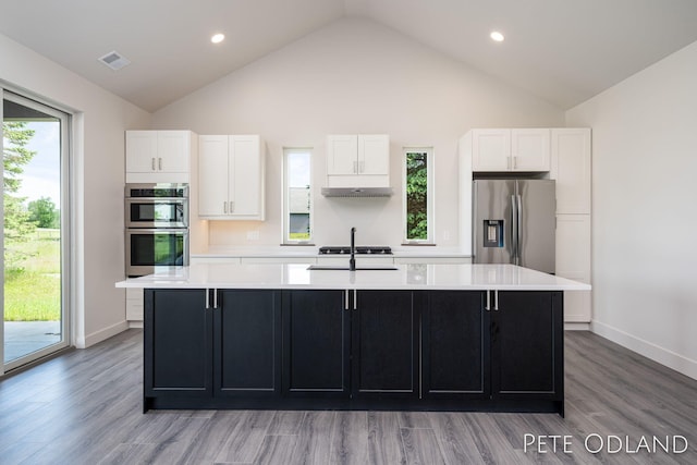 kitchen featuring hardwood / wood-style flooring, stainless steel appliances, an island with sink, and white cabinets