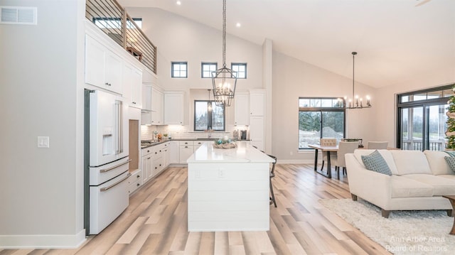 kitchen featuring high end fridge, white cabinets, decorative backsplash, and a chandelier