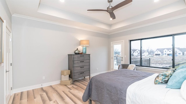 bedroom with light hardwood / wood-style flooring, ceiling fan, and a tray ceiling