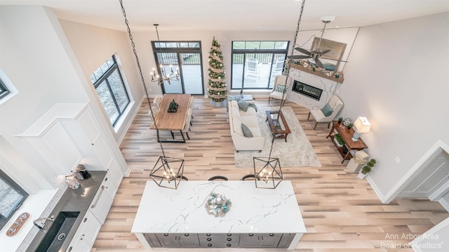 living room with a towering ceiling, a fireplace, light hardwood / wood-style flooring, and a notable chandelier