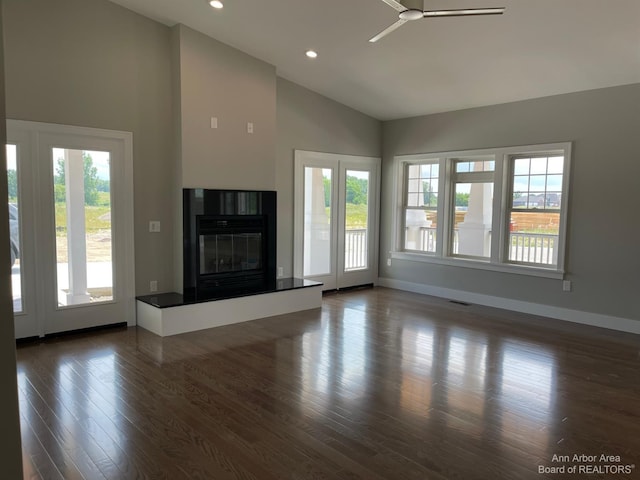 unfurnished living room featuring dark hardwood / wood-style flooring, a wealth of natural light, high vaulted ceiling, and ceiling fan