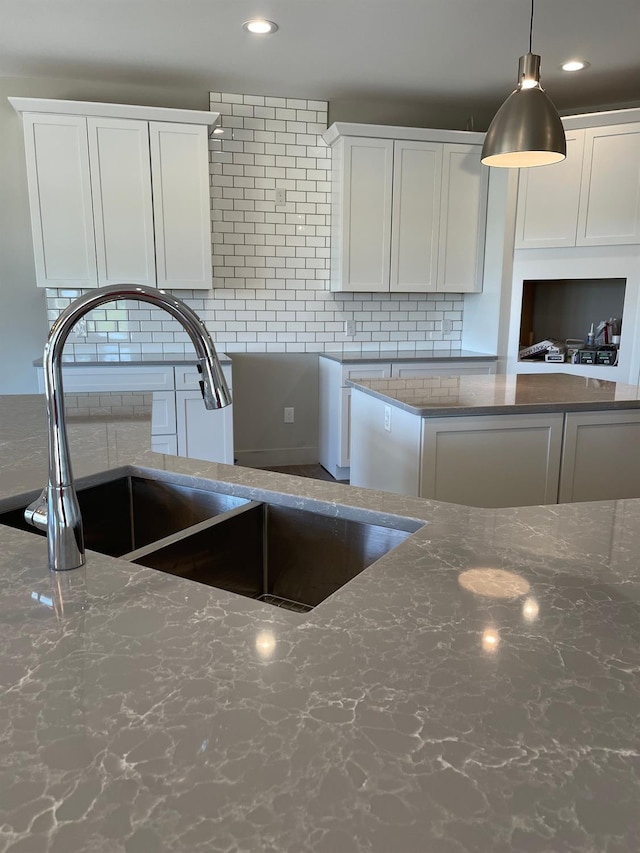 kitchen featuring white cabinetry, sink, decorative backsplash, and hanging light fixtures