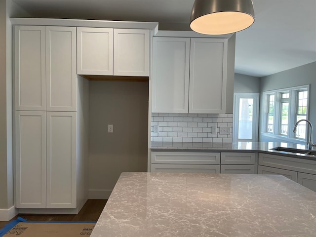 kitchen featuring white cabinets, sink, backsplash, and light stone counters