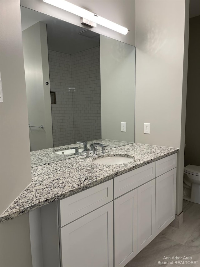 bathroom featuring vanity, toilet, and tiled shower