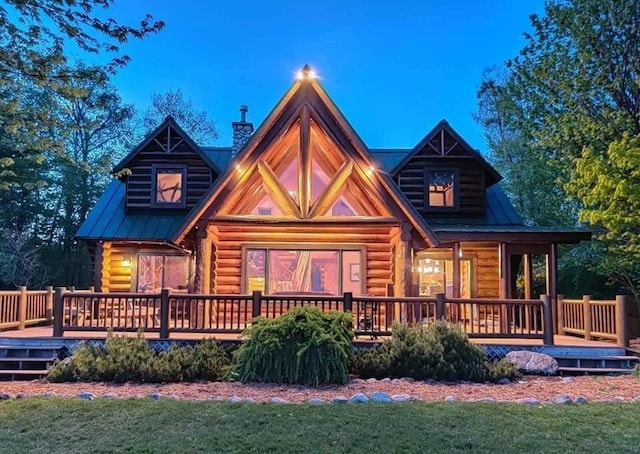 rear view of property featuring log siding, a chimney, and a yard